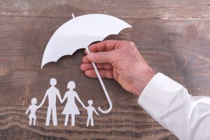 Hand holding an umbrella to protect family - insurance concept